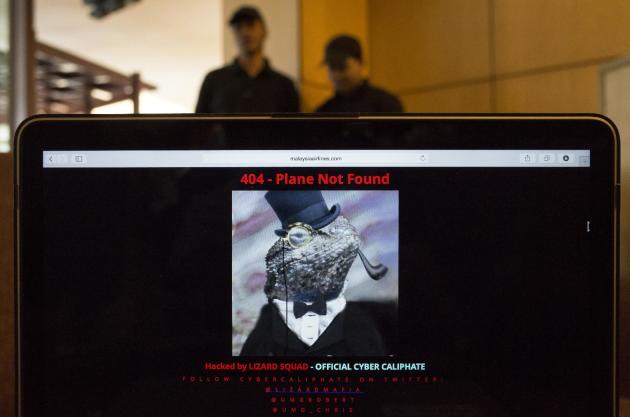 Workers stand behind a computer which shows the hacked website of Malaysia Airlines, at a cafe in Petaling Jaya outside Kuala Lumpur, Malaysia, Monday, Jan. 26, 2015. The airline's site was changed on Monday, at first with a message saying "404 - Plane Not Found" and that it was "Hacked by Cyber Caliphate." The browser tab for the website said "ISIS will prevail." (AP Photo/Joshua Paul)