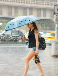 　行個方便　　台北市28日上午天氣炎熱晴朗，午後對流旺盛，下起又大又急的雨，一位民眾索性將鞋子脫掉，拎在手上，赤腳走在台北車站的街頭。（實習攝影馬向恩攝）