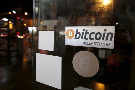 A bitcoin sticker is seen in the window of the 'Vape Lab' cafe, where it is possible to both use and purchase the bitcoin currency, in London March 24, 2015. REUTERS/Peter Nicholls/Files