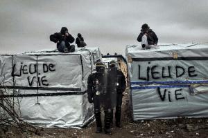 Policemen stand next to migrants on the roofs of their …