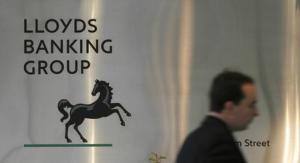 A man walks past a sign outside Lloyds Banking Group's headquarters in the City of London