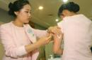 Una enfermera inyecta una vacuna contra la gripe a una colega el 27 de octubre de 2009 en Seúl
