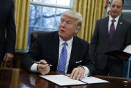 President Donald Trump signs an executive order to withdraw the U.S. from the 12-nation Trans-Pacific Partnership trade pact agreed to under the Obama administration, Monday, Jan. 23, 2017, in the Oval Office of the White House in Washington. (AP Photo/Evan Vucci)