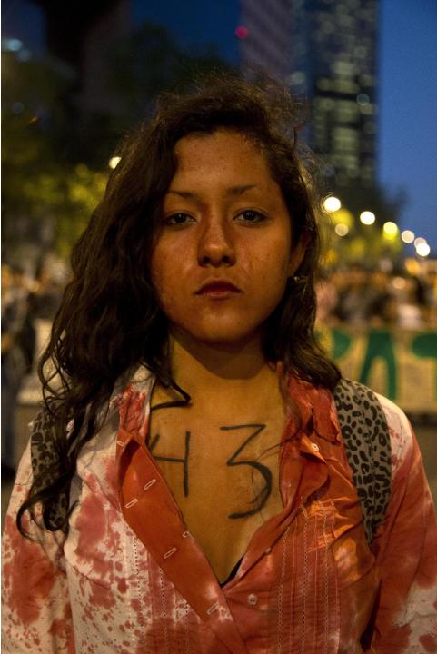 En esta imagen del 1 de diciembre de 2014, una manifestante cubierta de pintura roja y con el número de estudiantes desaparecidos en Iguala participa en una protesta en Ciudad de México. Se produjeron