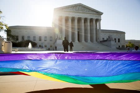 Gay marriage supporters hold a gay rights flag in front of the Supreme Court before a hearing about gay marriage in Washington April 28, 2015. REUTERS/Joshua Roberts