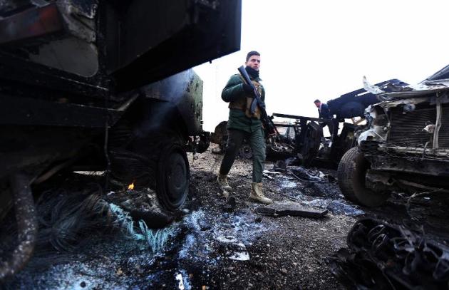 Un combatiente 'peshmerga' camina entre vehículos quemados tras un atentado suicida del grupo 'yihadista' Estado Islámico en Kesarej, al sur de Kumar, en Irak, el 18 de diciembre de 2014