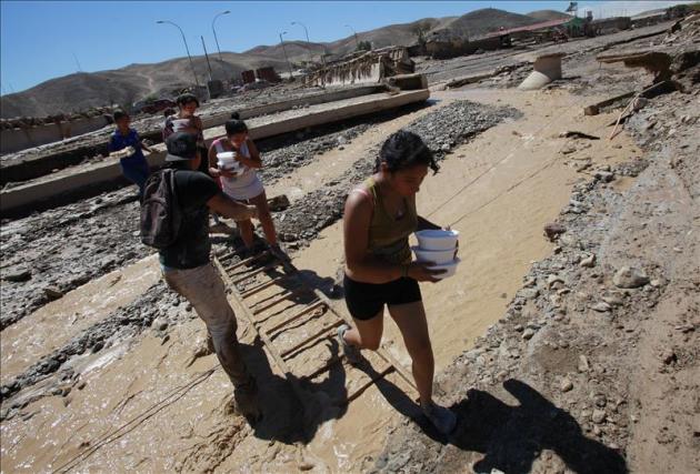 Un grupo de mujeres cruza un río con comida para distribuir este sábado 28 de marzo de 2015, tras las inundaciones de hace tres días, en un barrio en la localidad Diego de Almagro, a 1000 kilómetros al norte de Santiago de Chile (Chile). EFE
