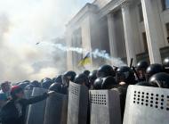 A demonstrator holds a police officer's shield in front of the parliament building in Kiev as smoke rises from the building during clashes with police officers on August 31, 2015
