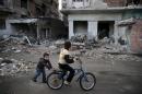 Children play on a bicycle near damaged buildings in   the town of Douma, eastern Ghouta in Damascus
