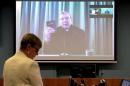 Senior Counsel Assisting Gail Furness stands in front   of a screen displaying Australian Cardinal George Pell as he holds a bible while   appearing via video link from a hotel in Rome, Italy to testify at the   Australia's Royal Commission into Institutional Re