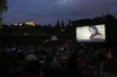 In this July 23, 2014 photo, people watch the movie "The Immigrant " at the Thisio outdoor summer cinema as the Ancient Acropolis is seen lit up in the background. Cine Thisio is one of the oldest open-air movie theaters in Athens, built in 1935. (AP Photo/Petros Giannakouris)