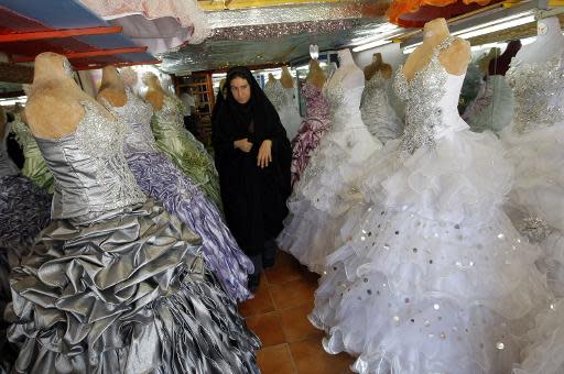 An Iranian woman walks past gowns and wedding dresses at a shop in Islamshahr, 50 kms (31 miles) southwest of Tehran, on May 30, 2009