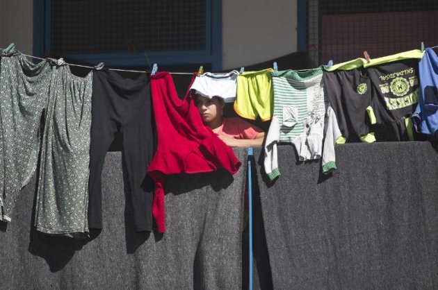 Una niña palestina refugiada por gestión de la ONU, observa junto a la ropa colgada en un balcón la visita de la nueva jefa de la diplomacia de la Unión Europea, Federica Mogherini, el 8 de noviembre de 2014 en Gaza