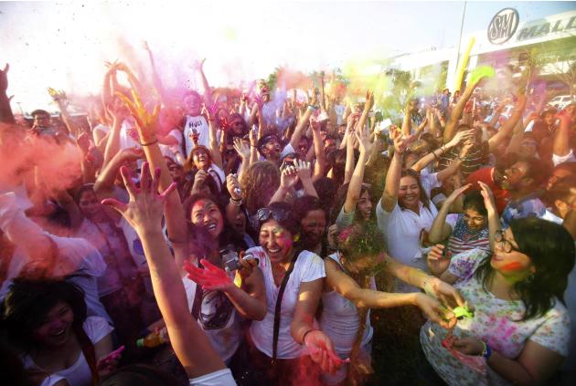 A crowd cheer and dance as they throw coloured powder in the air during celebrations for the Holi Festival in Pasay city