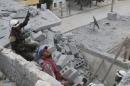 Civil defense members work at a site hit by an airstrike in the rebel held area of Aleppo's Baedeen district
