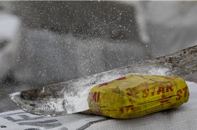 En esta imagen del 5 de diciembre de 2014, polvo en el aire después de que un agente antidroga abra un paquete de cocaína con un machete antes de su incineración a las afueras de Ciudad de Panamá. Seg