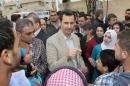 In this photo taken on Sunday, April 20, 2014 and released by the Syrian official news agency SANA, Syrian President Bashar Assad, center, speaks with Syrian citizens during his visit to Ain al-Tineh village, near Damascus, Syria. Assad visited on Sunday a historic Christian village his forces recently captured from rebels, state media said, as the country's Greek Orthodox Patriarch vowed that Christians in the war-ravaged country "will not submit and yield" to extremists. The rebels, including fighters from the al-Qaida-affiliated Nusra Front, took Maaloula several times late last year. (AP Photo/SANA)