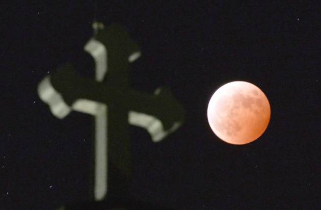 The Moon is bathed in a red light during a lunar eclipse seen over Tabira Cathedral in Hirado, southern Japan, Wednesday, Oct. 8, 2014. (AP Photo/Kyodo News) JAPAN OUT, MANDATORY CREDIT