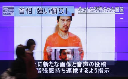 People walk past television screens displaying a news program, about an Islamic State video showing Japanese captive Kenji Goto, on a street in Tokyo January 28, 2015. REUTERS/Yuya Shino