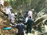 This image taken from video provided by Lao National TV, shows rescue workers at the where a Lao air force plane crashed in a forested area of Xiangkhoung province, Laos Saturday, May 17, 2014. The Lao air force plane carrying senior government officials crashed Saturday, killing at least five people on board, including the country's Defense Minister Douangchay Phichit, Thai officials said. (AP Photo/Lao National TV via AP Video) LAOS OUT, TV OUT