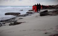 (Reprodução de vídeo) Dez homens com roupa laranja são conduzidos por sequestradores do EI, vestidos de preto, em uma praia de Trípoli, neste domingo