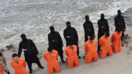 Men in orange jumpsuits purported to be Egyptian Christians held captive by the Islamic State (IS) kneel in front of armed men along a beach said to be near Tripoli, in this still image from an undated video made available on social media on February 15, 2015. REUTERS/Social media via Reuters TV