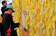 A South Korean woman attaches a yellow ribbon of hope for the safe return of missing passengers as people attend a memorial for the victims of the sunken South Korean ferry "Sewol" in Seoul on April 28, 2014