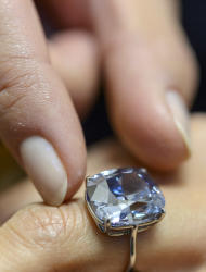 FILE - In this Nov. 4, 2015 file photo a Sotheby's employee displays the rare Blue Moon Diamond during a preview at Sotheby's, in Geneva, Switzerland. The 12.03 carat blue diamond is the largest cushion shaped fancy vivid blue diamond ever appear at auction. It is estimated to sell between 35-55 million US dollars. The auction will take place in Geneva, on Nov. 11, 2015. (Martial Trezzini/Keystone via AP, file)