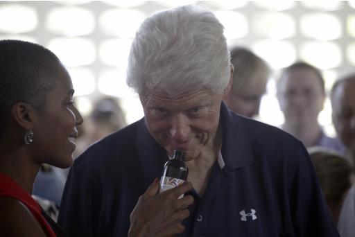 Former U.S. President Clinton smells from a bottle during a visit to Kreyol Essence, a Haitian women owned and operated company in Mirebalais