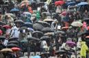 El público que asiste a un partido del Roland Garros en París el 29 de mayo de 2016 se protege de la lluvia