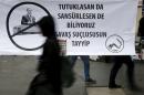 A woman walks past a banner during a protest over the   arrest of journalists Can Dundar and Erdem Gul in Ankara