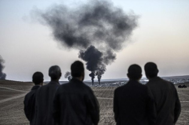 Varios hombres observan el humo elevándose de la localidad siria de Kobane, el 26 de octubre de 2014, vista desde la localidad fronteriza turca de Mursitpinar