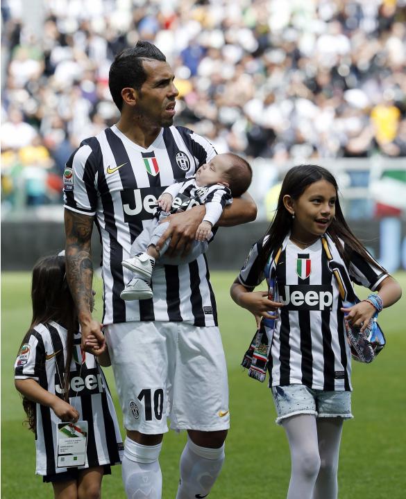 Juventus' Carlos Tevez arrives on the pitch with his children before the start of their Italian Serie A soccer match against Cagliari at Juventus stadium in Turin