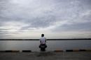 A Bangladeshi migrant who arrived recently by boat   sits on a dock near a temporary shelter in Kuala Langsa