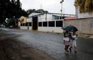 In this Thursday, Aug. 20, 2015 photo, people walk near a factory where Aragua State police officers killed four men execution-style in Maracay, Venezuela. A video secretly recorded that rainy day in early August showed that police officers took the man to a concrete alley in the complex where his three companions already lay dead, held him in place, and then shot him point blank. (AP Photo/Fernando Llano)