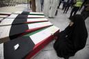 A woman grieves next to coffins of victims of   Friday's bombing at the Imam Sadeq mosque in Kuwait City, at the   international airport in Najaf