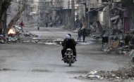 Una pareja conduce una motocicleta en una calle con escombros de edificios dañados en Deir al-Zor. Imagen de archivo, 05 marzo, 2014. Ataques aéreos y con misiles que habrían sido llevados a cabo por las fuerzas lideradas por Estados Unidos alcanzaron durante la noche y en la madrugada del viernes yacimientos petroleros y bases del Estado Islámico en la provincia de Deir al-Zor, en el este de Siria, dijo un grupo de seguimiento. REUTERS/Stringer