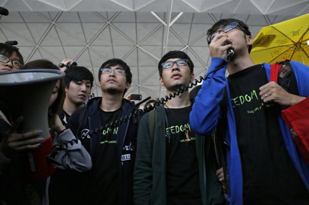 Hong Kong Federation of Students leader Alex Chow, left, committee members Nathan Law, center, and Eason Chung speak to supporters before attempting to travel to Beijing, at Hong Kong International Airport Saturday, Nov. 15, 2014. Three students who have led protests for greater democracy in Hong Kong were denied permission to travel to Beijing to meet with China's top officials. (AP Photo/Vincent Yu)