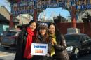 Guo Miao (d) y dos amigas posan con un mensaje para el niño estadounidense de ocho años enfermo de cáncer en fase terminal Dorian Murray enfrente del Templo Lama de Pekín