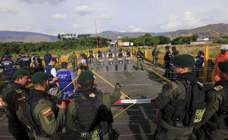 Colombian policemen stand guard in front of the border with Venezuelan policemen Bolivarianos near Villa del Rosario village, August 27, 2015. REUTERS/Jose Miguel Gomez