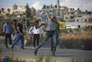 A Palestinian demonstrator hurls a stone during clashes with Israeli troops near Ramallah, West Bank, Tuesday, Sept. 29, 2015. Palestinian demonstrators clashed with Israeli troops across the West Bank on Tuesday as tensions remained high following days of violence at Jerusalem's most sensitive holy site, revered by Jews as the Temple Mount and by Muslims as the Noble Sanctuary. (AP Photo/Majdi Mohammed)