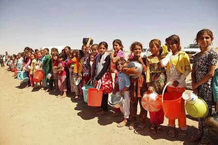 Várias pessoas da minoria yazidi, fugidas da violência na cidade iraquiana de Sinjar, fazem fila para receber alimentos num acampamento nos arredores da província de Dohuk, em setembro. 13/09/2014 REUTERS/Ari Jalal