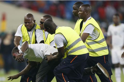 Security detain an Equitorial Guinea fan on the pitch after he tried to attack the referee during the African Cup semi-final match against Ghana in Malabo