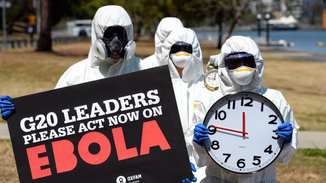 Protestors carry clocks to show time is running out during an Ebola 