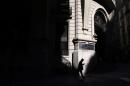 A man is silhouetted as he looks at his phone while walking in Buenos Aires' financial district