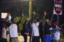 Demonstrators stand in the middle of West Florissant   holding a street sign, with their hands up, towards the police during ongoing   protests in reaction to the shooting of teenager Michael Brown in Ferguson