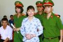 Can Thi Theu, a farmer and land protection activist   is escorted by policemen at a court in Hanoi, Vietnam