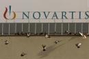 Pigeons sit on a roof in front of the logo of Swiss drugmaker Novartis at the company's plant in Basel