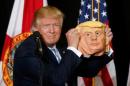 Republican presidential nominee Donald Trump holds up   a mask of himself as he speaks during a campaign rally in Sarasota