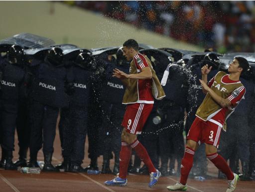 Equatorial Guinea's players dodge water bottles thrown by fans as police protect Ghana players during their semi-final soccer match of the 2015 African Cup of Nations in Malabo